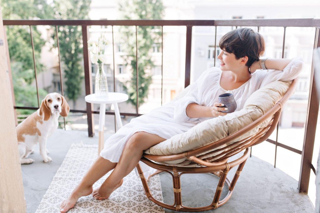 Adorable girl with short hair drinking coffee on balcony