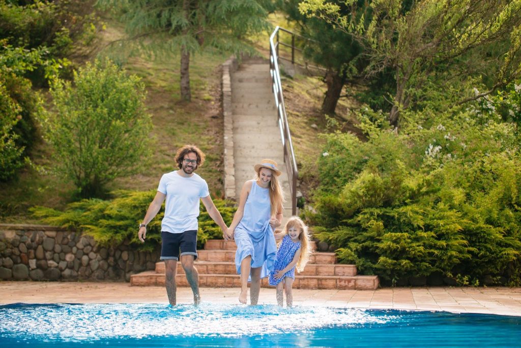 family having fun and splashing water with legs or hands in swimming pool